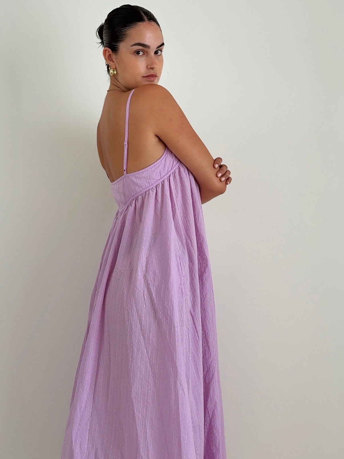 Woman wearing a long purple dress against a plain background